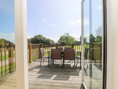 a patio with a table and chairs on a deck at Rowan in Truro