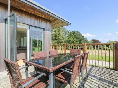 a patio with a glass table and chairs on a deck at Rowan in Truro