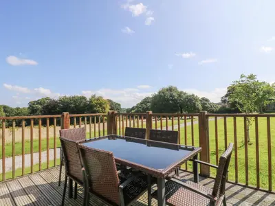 a table and chairs on a deck with a fence at Rowan in Truro