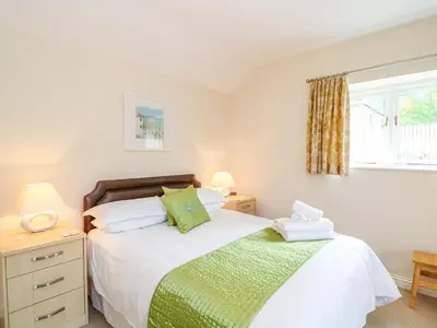 a bedroom with a bed and two lamps and a window at Forget-me-not in Saint Columb Major