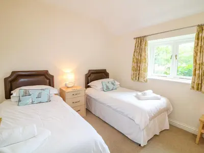 two beds in a room with a window at Forget-me-not in Saint Columb Major