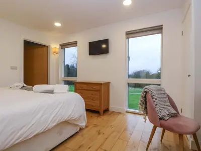 a bedroom with a bed and a chair and windows at Oak in Truro