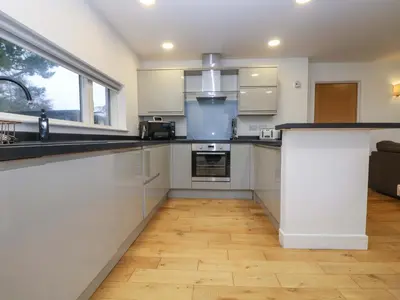 a kitchen with white cabinets and a large window at Oak in Truro