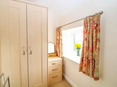 a bedroom with a mirror and a window and a dresser at Cornflower Cottage in Saint Columb Major