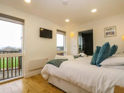 a bedroom with a bed and a balcony at Juniper in Truro