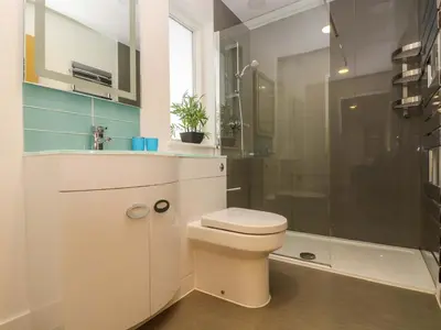 a white bathroom with a toilet and a shower at Juniper in Truro