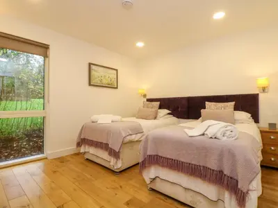 two beds in a room with a window at Juniper in Truro