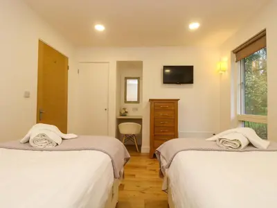 a bedroom with two beds and a television on the wall at Juniper in Truro