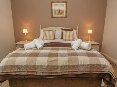 a bedroom with a large bed with two lamps at 64 Waterside in Bodmin