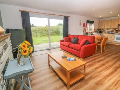 a living room with a red couch and a table at 64 Waterside in Bodmin