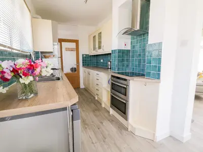 a kitchen with white cabinets and a vase of flowers at Senafe in Bude