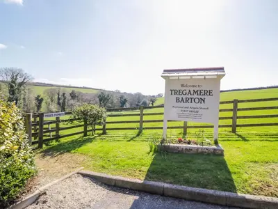 a sign in a field next to a fence at Lambkin Cottage in Saint Columb Major