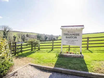 a sign in a field next to a fence at Lambkin Cottage in Saint Columb Major