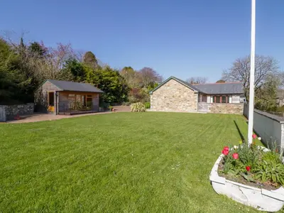 a yard with a house and a lawn with flowers at Lambkin Cottage in Saint Columb Major