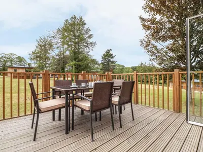 a patio with a table and chairs on a deck at Elm in Truro