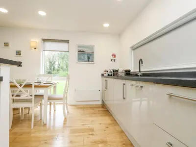 a kitchen with white cabinets and a dining room with a table at Birch in Truro