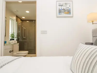 a bedroom with a white bed and a bathroom at Birch in Truro