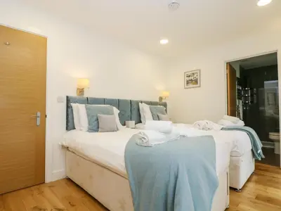 two white beds in a bedroom with a blue headboard at Beech in Truro