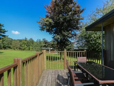 a wooden deck with two benches and a table on it at Beech in Truro