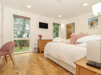 a white bedroom with a bed and a television at Ash in Truro