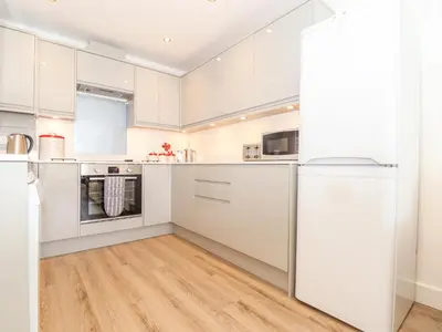 a kitchen with white cabinets and a hardwood floor at The Crest in Helston