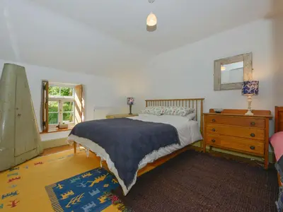 a bedroom with a bed and a dresser and a window at Heather Cottage in Penzance