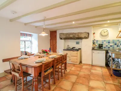a large kitchen with a wooden table and chairs at Heather Cottage in Penzance
