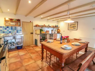 a kitchen with a wooden table in a room at Heather Cottage in Penzance