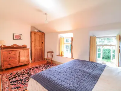 a bedroom with a bed and a dresser and windows at Heather Cottage in Penzance