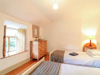 a bedroom with two beds and a window at Heather Cottage in Penzance