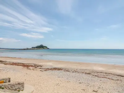 an empty beach with an island in the ocean at Heather Cottage in Penzance