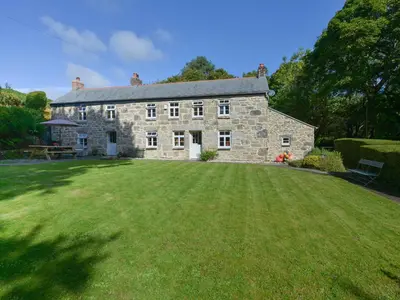 a large stone house with a large grass yard at Heather Cottage in Penzance