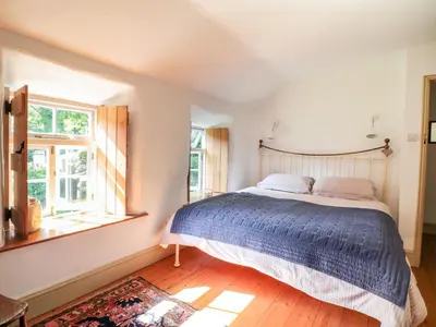 a bedroom with a large bed and a window at Heather Cottage in Penzance