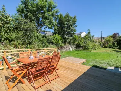 a wooden deck with a wooden table and chairs at Manor House Barn in Camelford