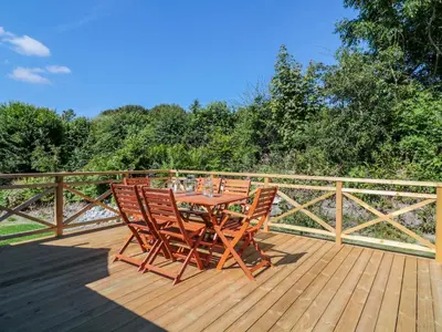a wooden table and chairs on a deck at Manor House Barn in Camelford