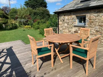 a wooden table and chairs on a wooden deck at Manor House Barn in Camelford