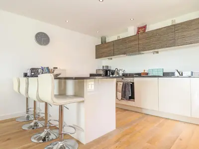 a kitchen with white cabinets and bar stools at 8 Cribbar in Newquay