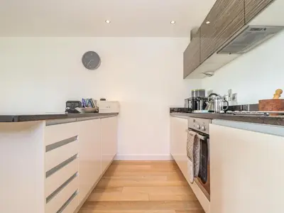 a kitchen with white cabinets and wooden floors at 8 Cribbar in Newquay