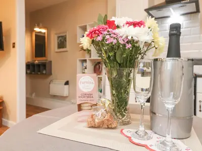 a table with a vase of flowers and a bottle of wine at The Roost in Camborne