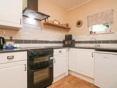 a kitchen with white cabinets and a black oven at The Roost in Camborne