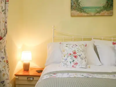 a bedroom with a bed and a lamp on a table at The Roost in Camborne