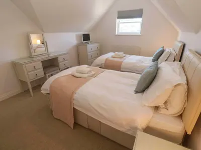 a bedroom with two beds and a desk at Meridian in St Ives