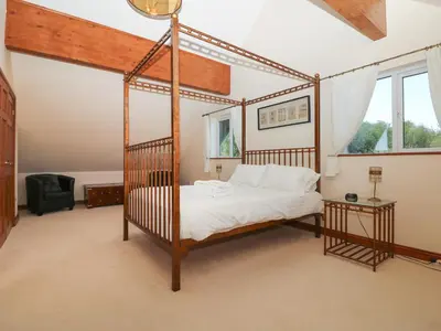 a bedroom with a four poster bed and a window at Willow, Retallack in Saint Columb Major