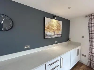 a kitchen with a clock and a tree on the wall at Willow, Retallack in Saint Columb Major