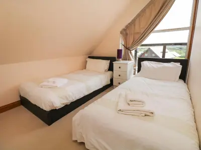 two beds in a room with a window at Willow, Retallack in Saint Columb Major