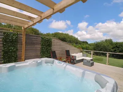 a hot tub on a deck with a pergola at Willow, Retallack in Saint Columb Major