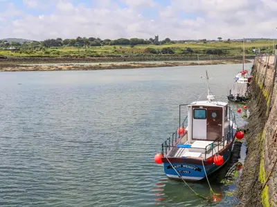 a small boat is docked in the water at Coth Skyber in Hayle