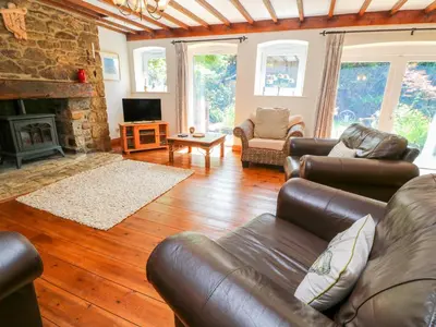 a living room with leather furniture and a fireplace at Coth Skyber in Hayle
