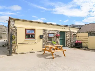 a wooden picnic table in front of a building at The Old Cows House in Helston