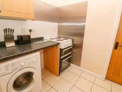 a kitchen with a washing machine and a stove at The Old Cows House in Helston